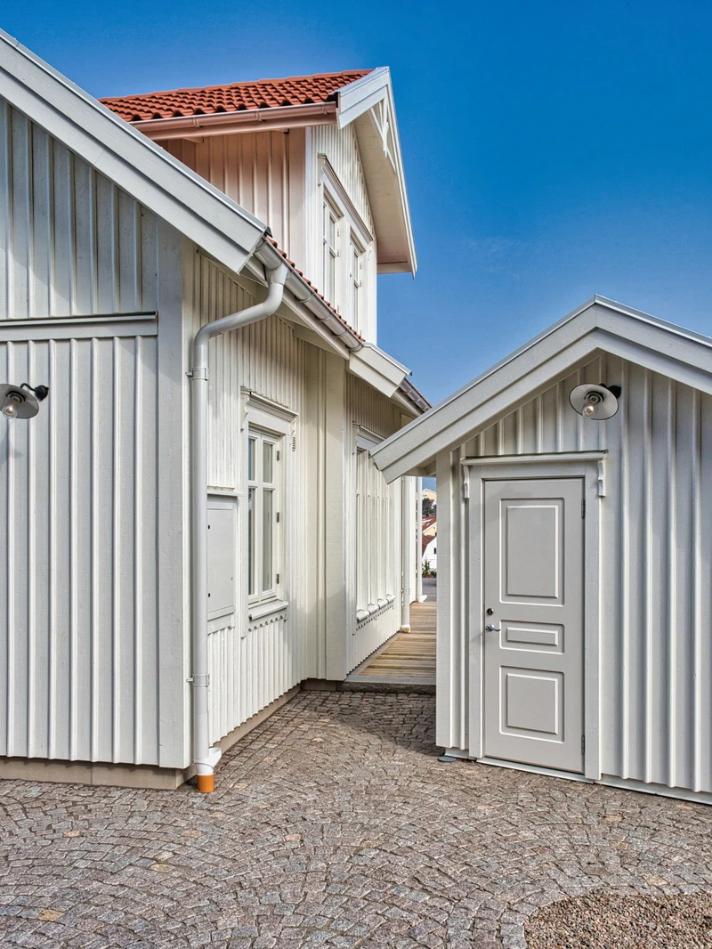 Vit träfasad med spröjsade fönster och rött tak, ur katalogen