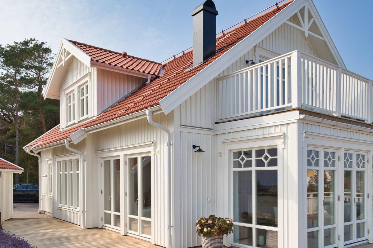 Vitt trähus i ett och ett halvt plan med rött tegeltak och vit träbalkong, Grundsund