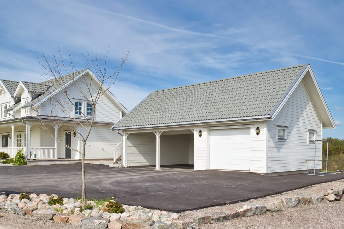 Vit villa med takkupor och fristående garage med carport