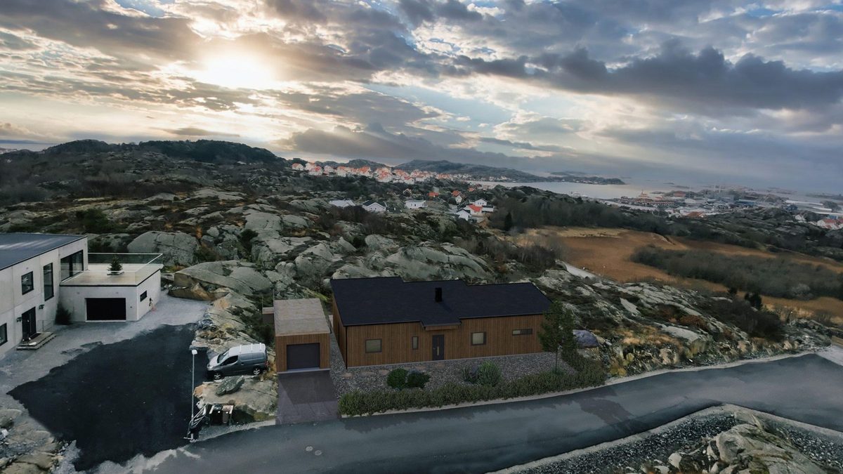 Illustration av ett mörkt trähus med svart tak på berget i Rönnäng, med utsikt mot havet