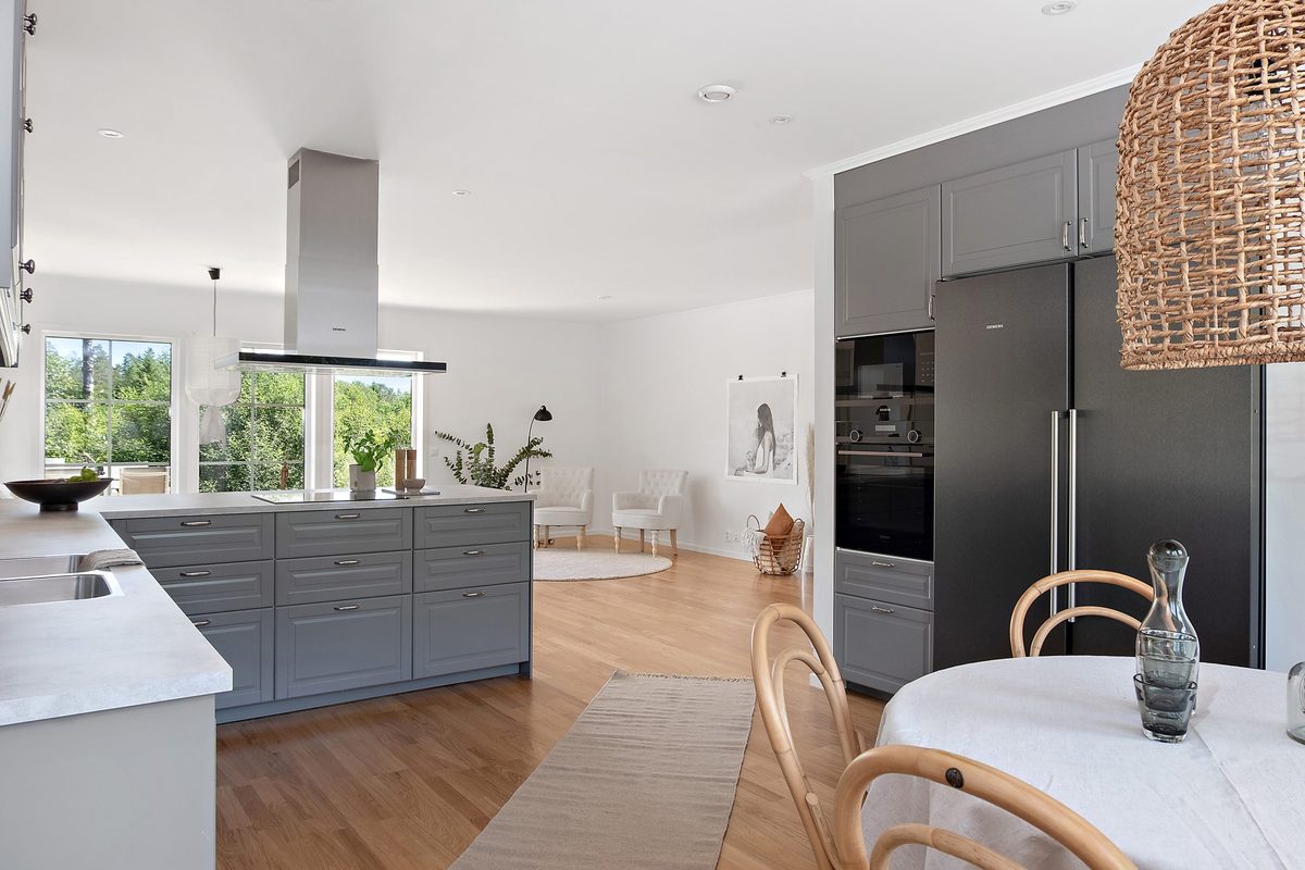Grått kök med köksö och ett matbord i förgrunden