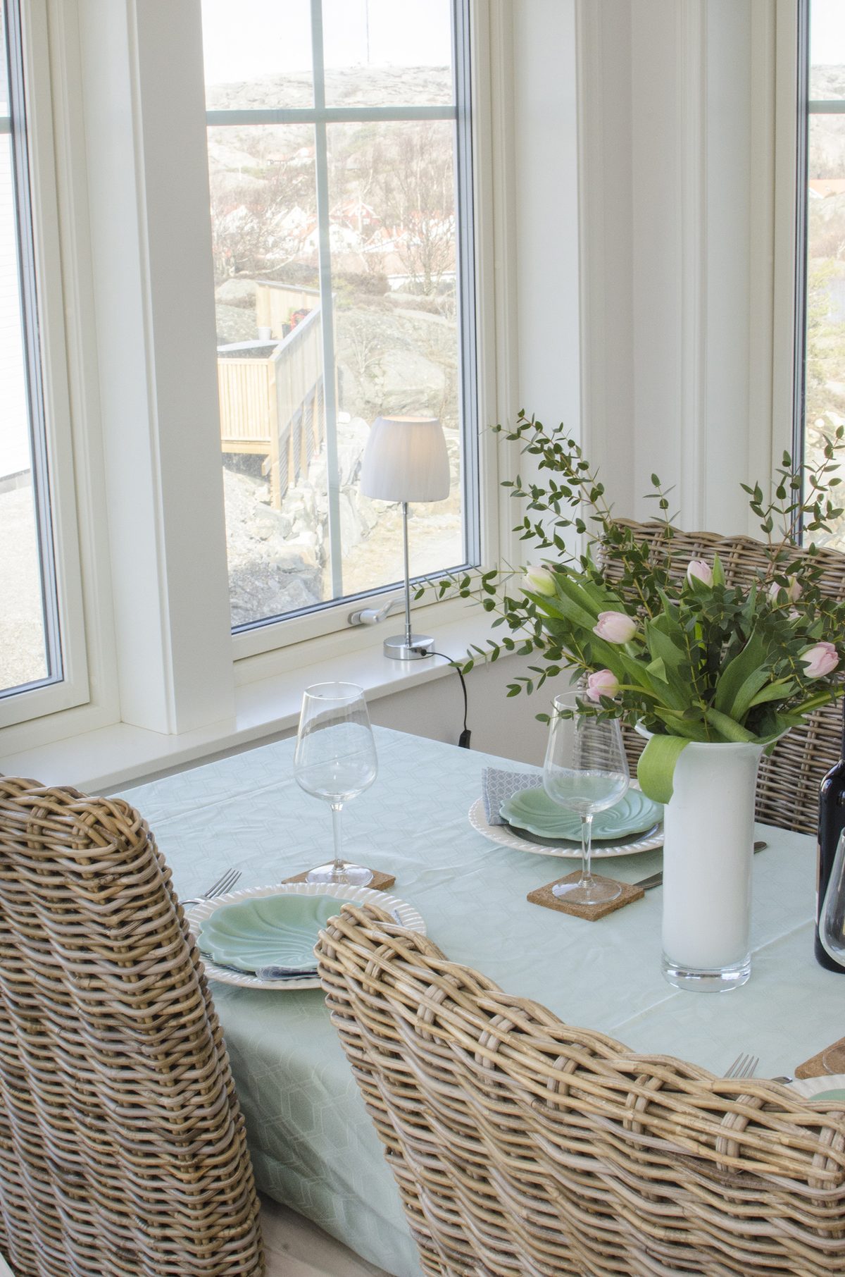 Dukat bord med tulpaner och flätad stol vid fönstret