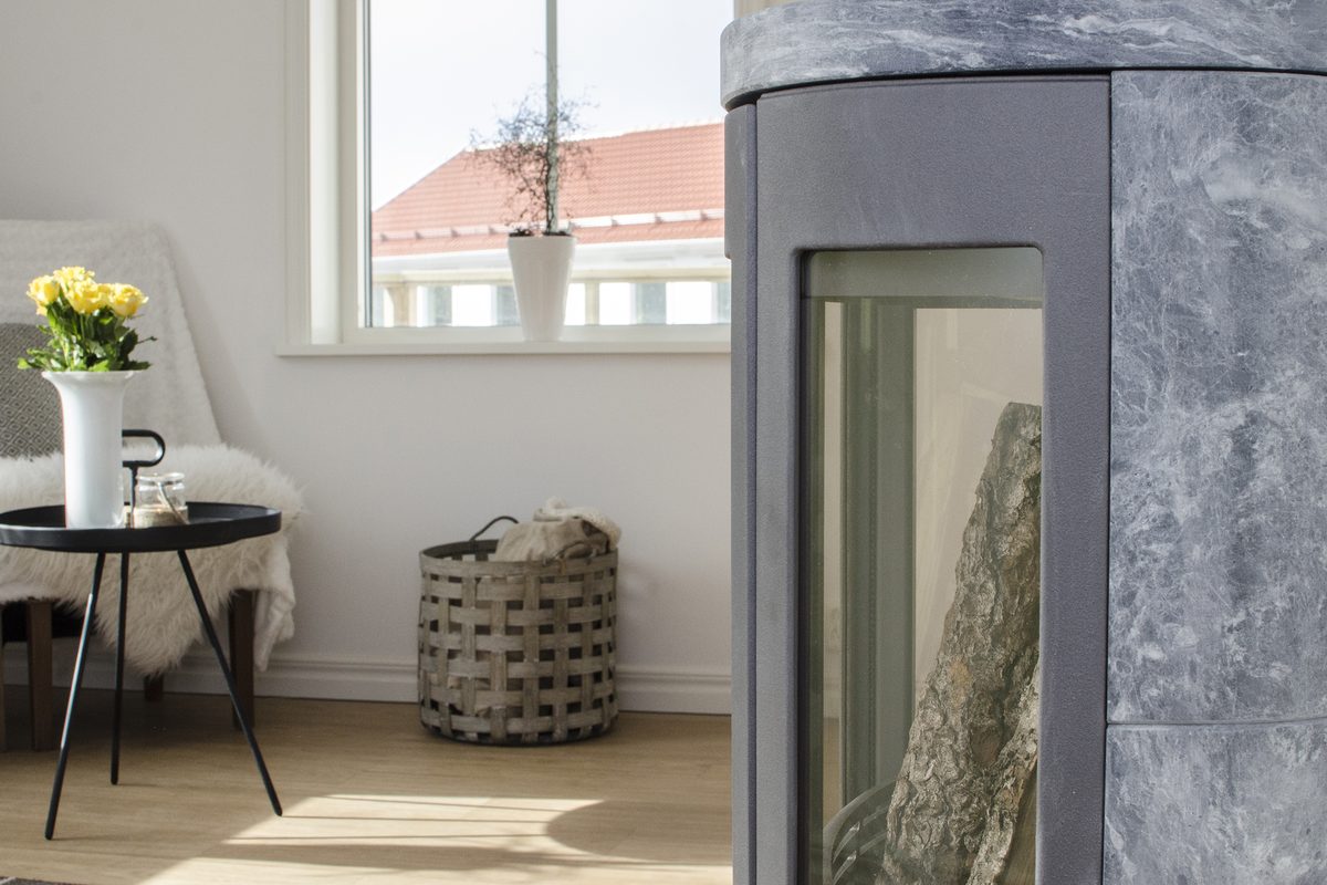 Grå kamin intill ett litet bord och ett fönster