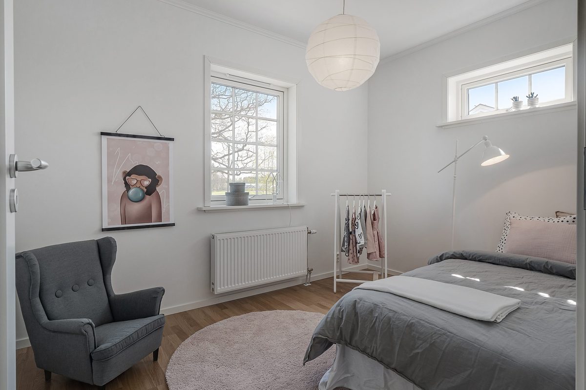 Sovrum med enkelsäng, fåtölj och spröjsat fönster