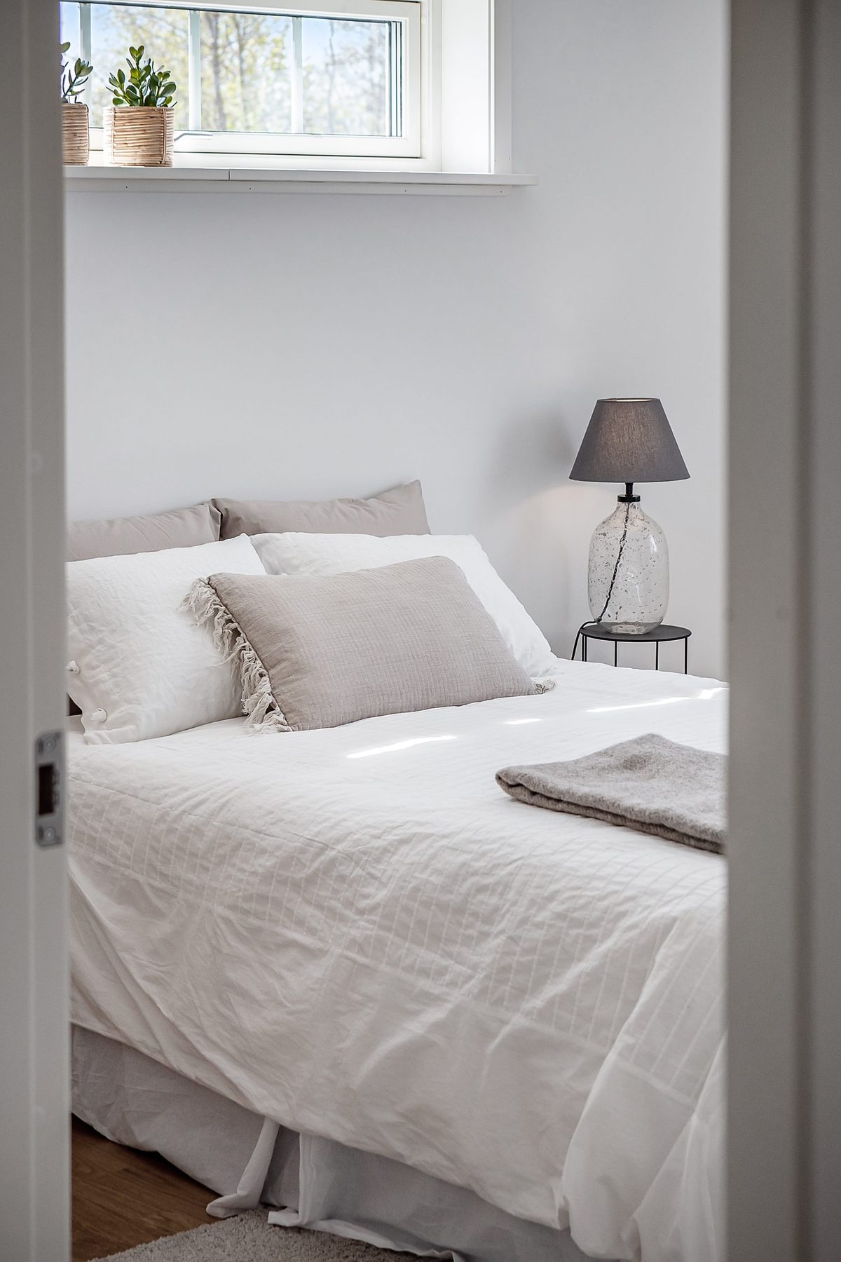 Detalj av en bäddad dubbelsäng med vitt överkast